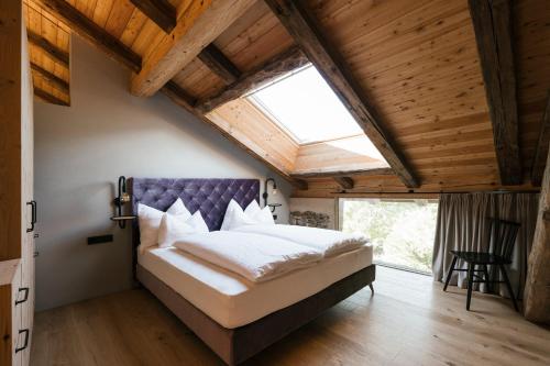 a bedroom with a large bed with a purple headboard at St. Vigilius modern historic apartments in Nalles