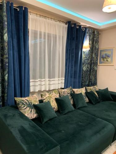 a living room with a green couch with blue curtains at Siedlisko Kępina Zdrój in Ostrów