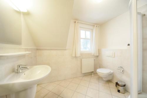 a white bathroom with a sink and a toilet at Kirr in Zingst