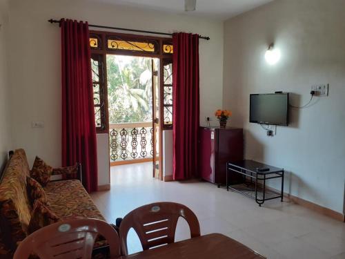 a living room with a couch and a tv at Antonio's Residency Goa in Betalbatim