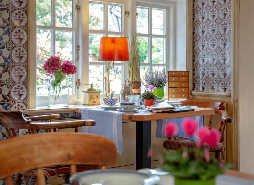 a room with a table with chairs and windows at Boutiquehotel Seiler Hof Keitum in Keitum