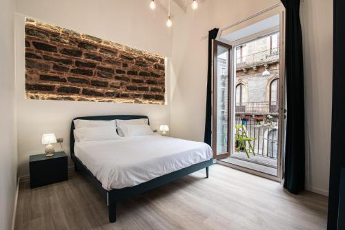 a bedroom with a bed and a brick wall at Il Moro Boutique Apartment in Catania
