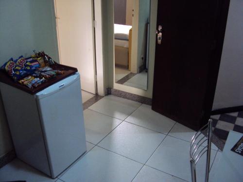 a room with a small refrigerator and a mirror at Estoril Hotel in Belo Horizonte