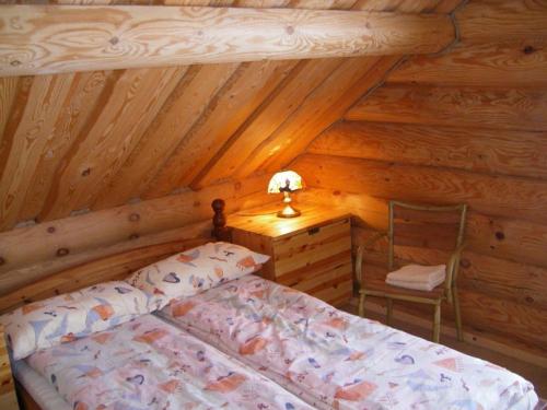 a bedroom with a bed in a log cabin at Sodyba Tarp Liepų in Leliūnai