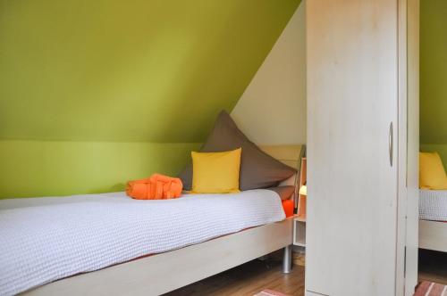 um quarto com paredes verdes e uma cama com almofadas amarelas e laranja em Auszeit Wrixum em Boldixum