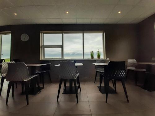 a restaurant with chairs and tables and a large window at Vagnsstadir Guesthouse in Borgarhöfn