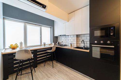 une cuisine avec des placards blancs et un comptoir avec des tabourets dans l'établissement Apartament Delux, à Bacău