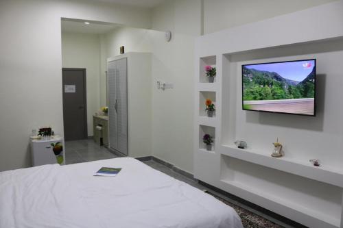 1 dormitorio con 1 cama y TV de pantalla plana en la pared en فندق زيلامسي en Ţarīf