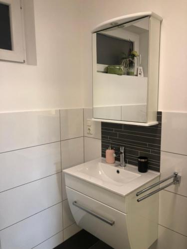 a white bathroom with a sink and a mirror at Ferienwohnungen Margot in Iserlohn