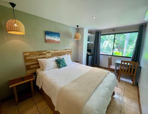 a bedroom with a large white bed and a table at Hotel El Manglar in Playa Grande