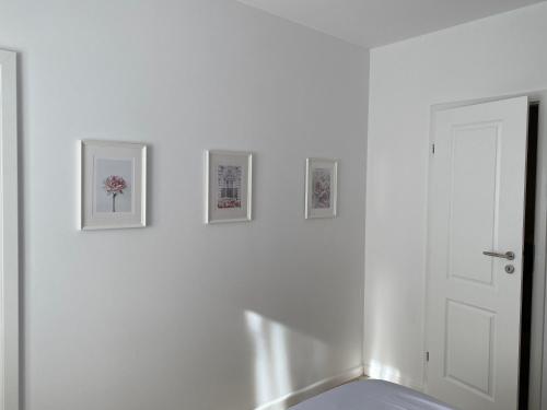 Habitación blanca con 3 cuadros en la pared en Magheru cozy new apartament 2 rooms, en Bucarest