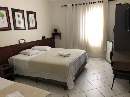 a bedroom with a bed with two towels on it at Hotel de Minas in Caxambu