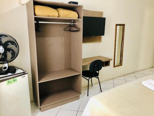 a room with a bed and a desk and a closet at Hotel de Minas in Caxambu