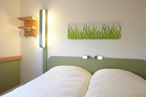 a bedroom with a bed with a green headboard at ibis budget Pontarlier in Pontarlier