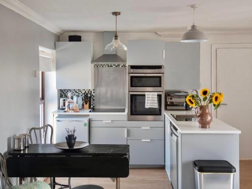 a kitchen with white cabinets and a table with flowers at Penarth Town (Cardiff) - Private Sun Terrace! Ideal For Families & Couples! in Cardiff