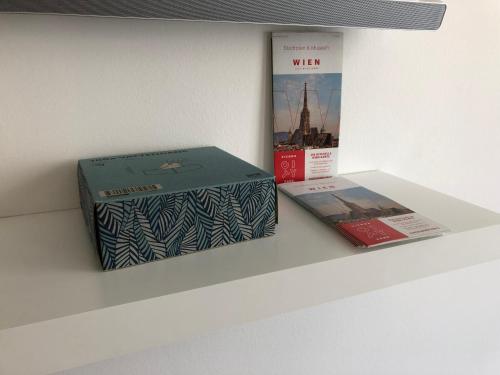 twee dozen op een plank met een boek bij Apartment Philip Vienna Self Check-In in Wenen