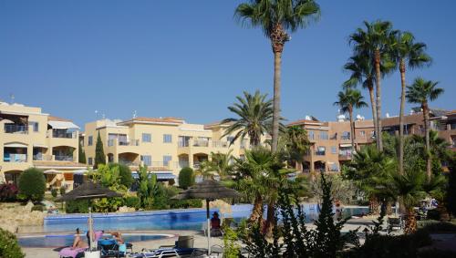 a view of a resort with palm trees and a swimming pool at Limnaria Gardens Paphos, near beach in Paphos