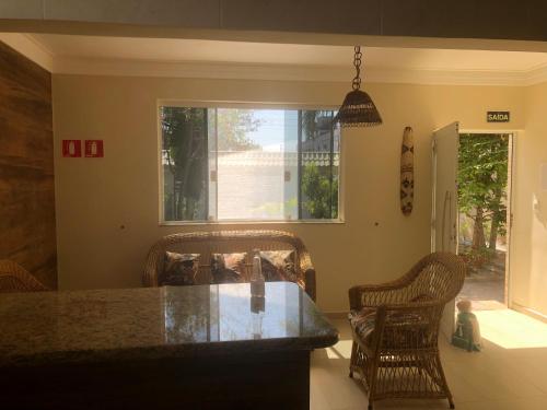 a kitchen with a counter and two chairs and a window at Suites Praia de Pernambuco in Guarujá