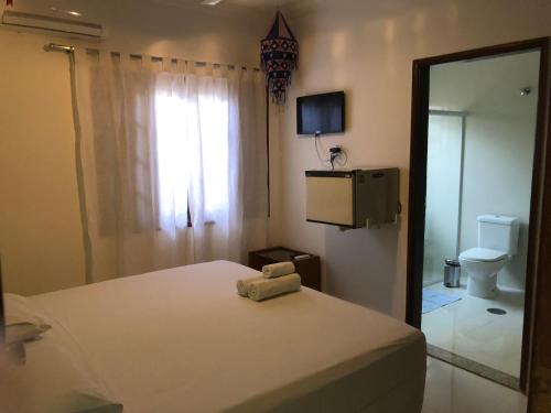 um quarto com uma cama, um WC e um espelho em Suites Praia de Pernambuco no Guarujá