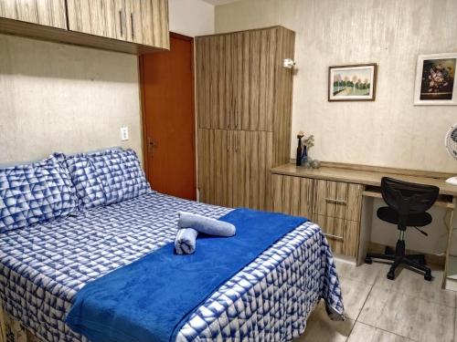 a bedroom with a bed with a blue comforter and a desk at Apartamento de 3 quartos no Marina Clube in Cabo Frio