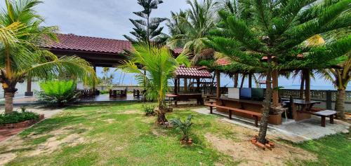 a resort with benches and palm trees in a yard at Bayu Beach Penarek in Penarek