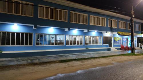 a blue building with a gas station at night at Hotel Rainha in Itapoa