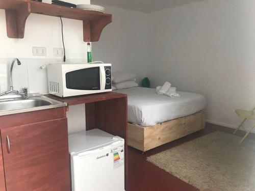 a small kitchen with a microwave and a bed at Tronador II - III - IV in Puerto Montt