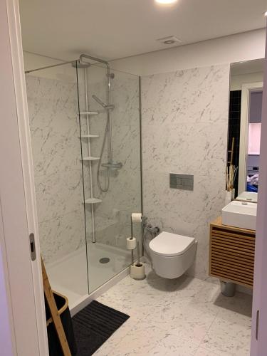 a bathroom with a shower and a toilet and a sink at Cozy canide beach apartment in Canidelo