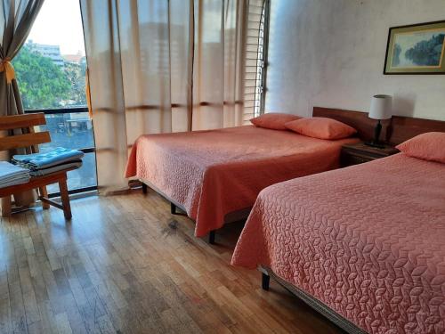 a hotel room with two beds and a window at Apartamento 505 Cortijo Reforma zona 9 in Guatemala
