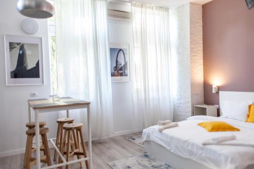 Dormitorio pequeño con cama, mesa y taburetes en Modern Studio in the Heart of Iasi, en Iaşi