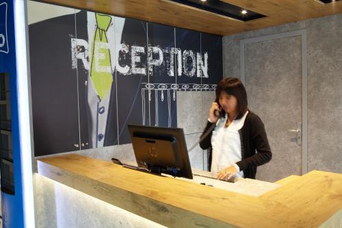 a woman talking on a phone at a desk with a computer at ibis budget Pontarlier in Pontarlier
