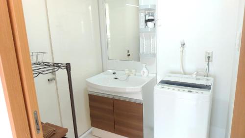 uma casa de banho com um lavatório e uma máquina de lavar roupa em コテージ花 em Motobu