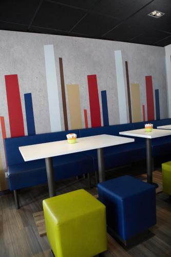 two tables with chairs and a wall with graphs at ibis budget Pontarlier in Pontarlier