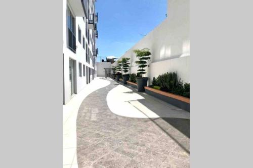 an empty street with a white building and plants at Departamento *MUNDO VIAJERO* Guadalajara in Guadalajara