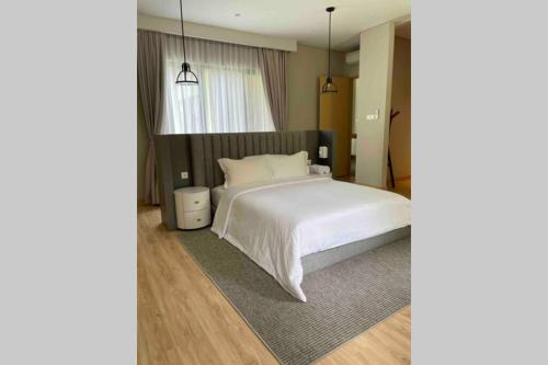 a bedroom with a white bed and a window at The Pines Vimala Hills in Bogor