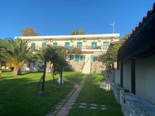 a building with palm trees in front of a yard at Angeliki Beach Hotel in Megali Ammos