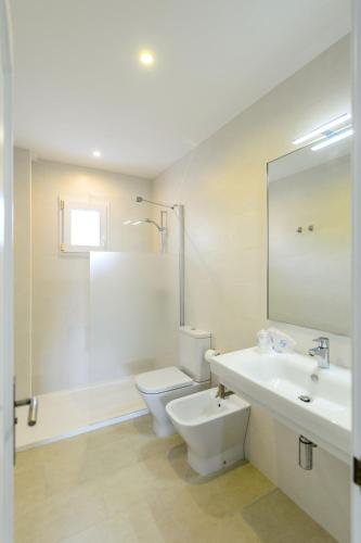a white bathroom with a toilet and a sink at Lili Apartments in Port de Soller