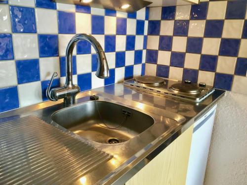 eine Spüle aus Edelstahl in einer Küche mit blauen und weißen Fliesen in der Unterkunft Studio Villard-de-Lans, 1 pièce, 4 personnes - FR-1-515-42 in Villard-de-Lans