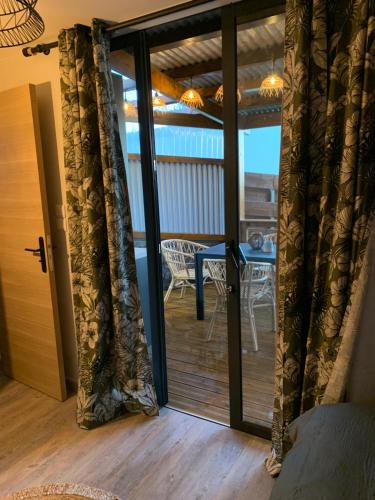 a sliding glass door leading to a deck with a table at Maison avec piscine chauffée - 8 personnes - Sud Réunion in Saint-Joseph