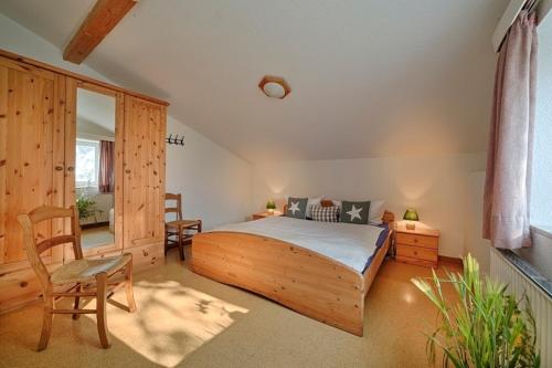a bedroom with a wooden bed and a chair at "Ferienhof Seelust" Ferienwohnung Nelke in Gammendorf