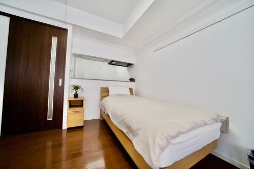 a white bedroom with a bed and a wooden door at Villa Izumizaki in Naha