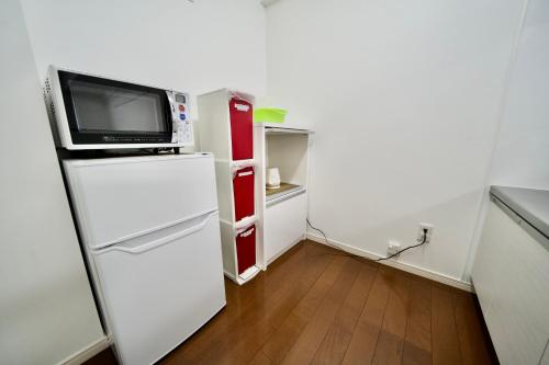 a small kitchen with a microwave on top of a refrigerator at Villa Izumizaki in Naha