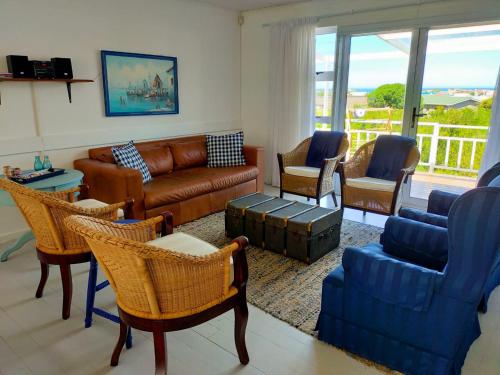 ein Wohnzimmer mit Couch und Stühlen in der Unterkunft Cottage Amnesia in Bettyʼs Bay