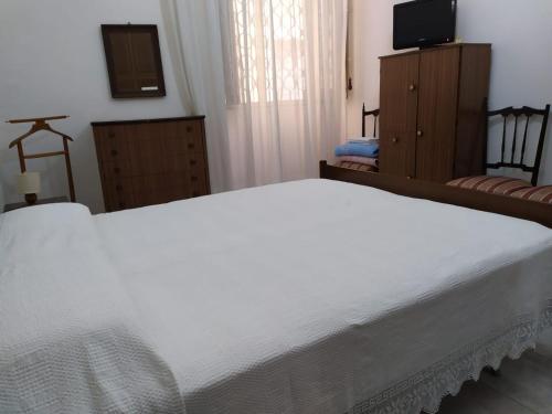 a bedroom with a white bed and a television at Casa ad Assoro, al centro della Sicilia in Assoro