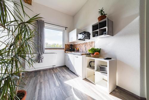 eine Küche mit weißen Schränken und einem großen Fenster in der Unterkunft Apartment 4 an der Messe Friedrichshafen in Friedrichshafen