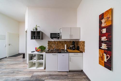 een keuken met witte kasten en een aanrecht bij ApartmentFinke 3 an der Messe Friedrichshafen in Friedrichshafen