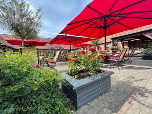 a patio with tables and chairs with red umbrellas at Landhotel Zur Schmiede in Göhren-Lebbin