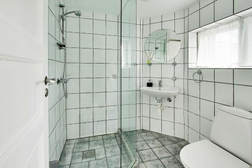 uma casa de banho com um lavatório, um WC e um espelho. em Holberggaard Apartments em Vordingborg