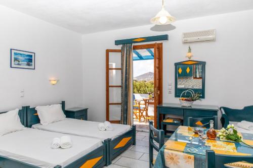 a room with two beds and a table and a balcony at Surfer Paradise in Naxos Chora