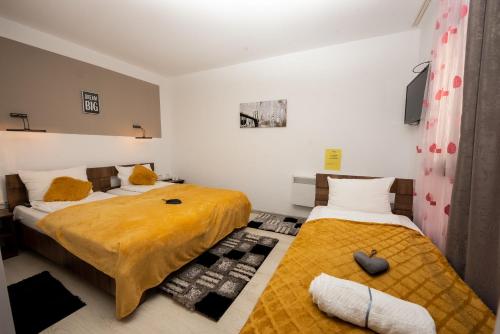 una camera da letto con due letti e una TV a parete di Complex Turistic Dávid a Boghiş